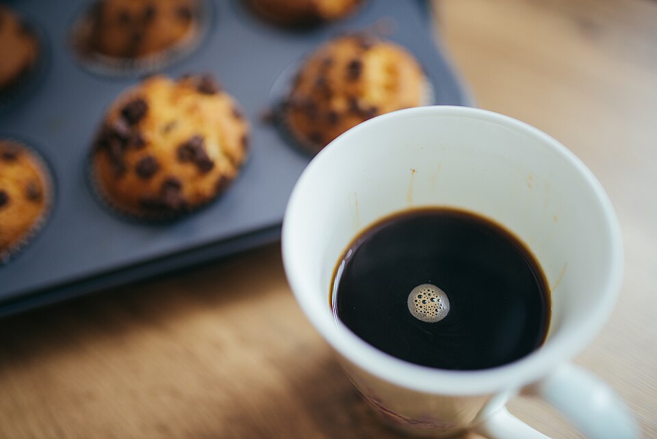 木のテーブルに置かれたコーヒーとマフィン