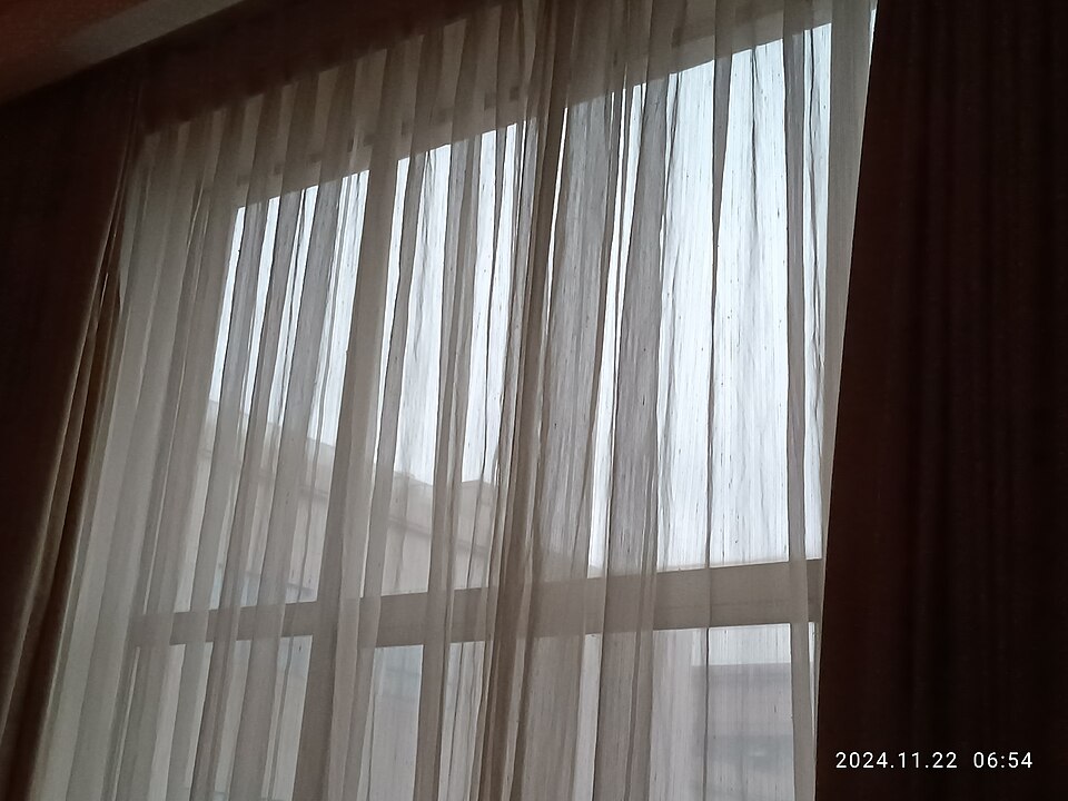 朝の光が差しこむ窓と白いカーテン