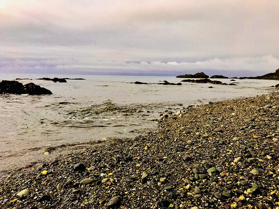 夕暮れの静かな海と石の多い岸辺