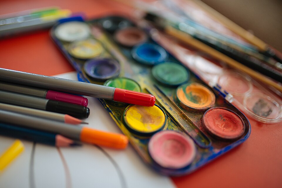 テーブルに並んだ絵の具やペンなどの画材