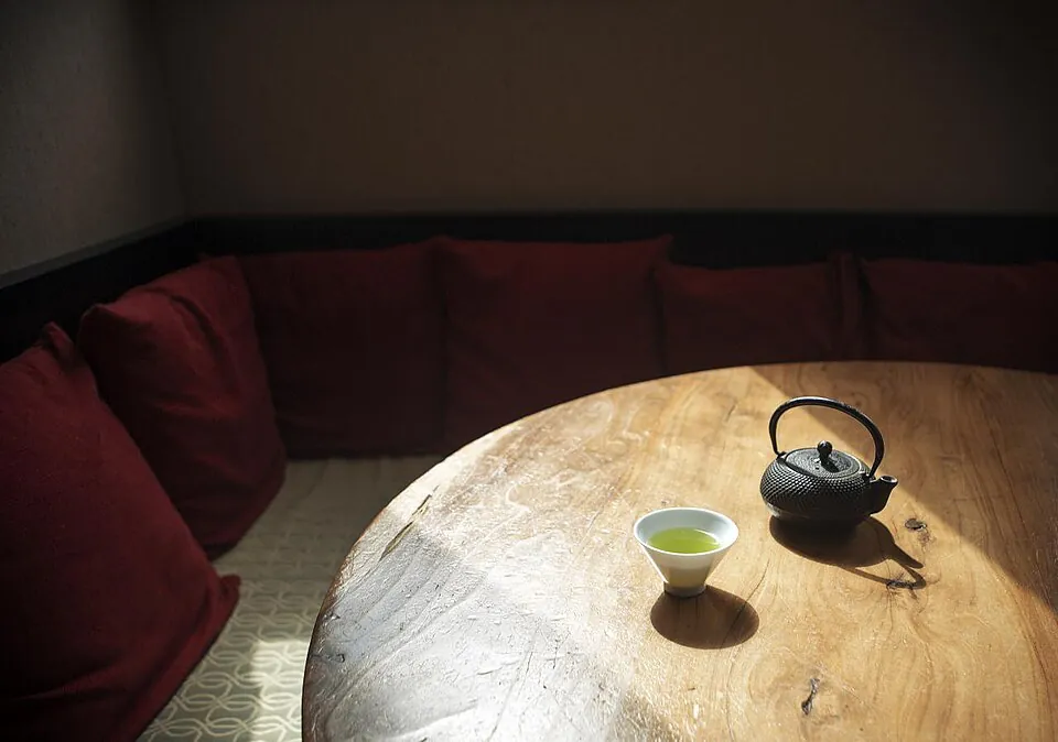 日の当たる木の丸テーブルに置かれた急須と湯のみ