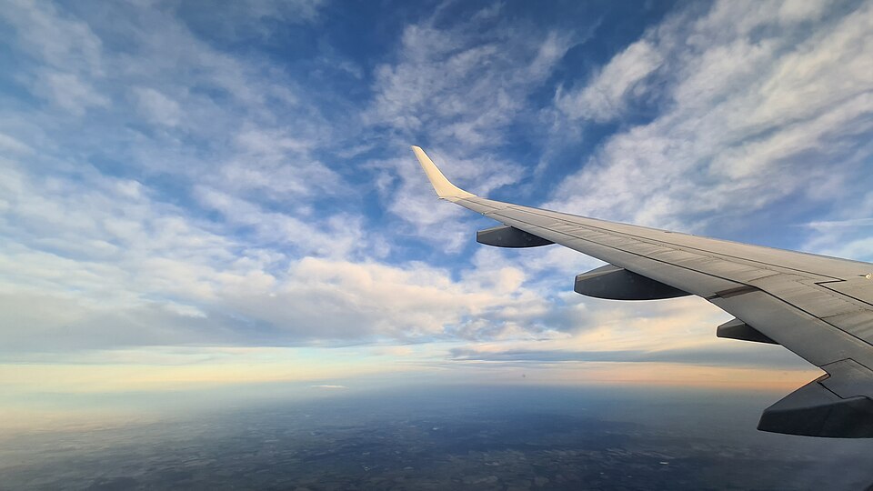 朝の光に染まる空と飛行機の翼